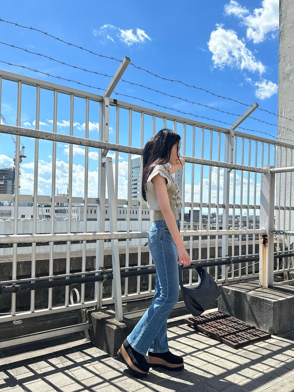 ホワイト系のニット/セーター、ブルー系のデニムパンツ、ブラック系のブーツを着用したレディースの夏コーディネートの3枚目の写真