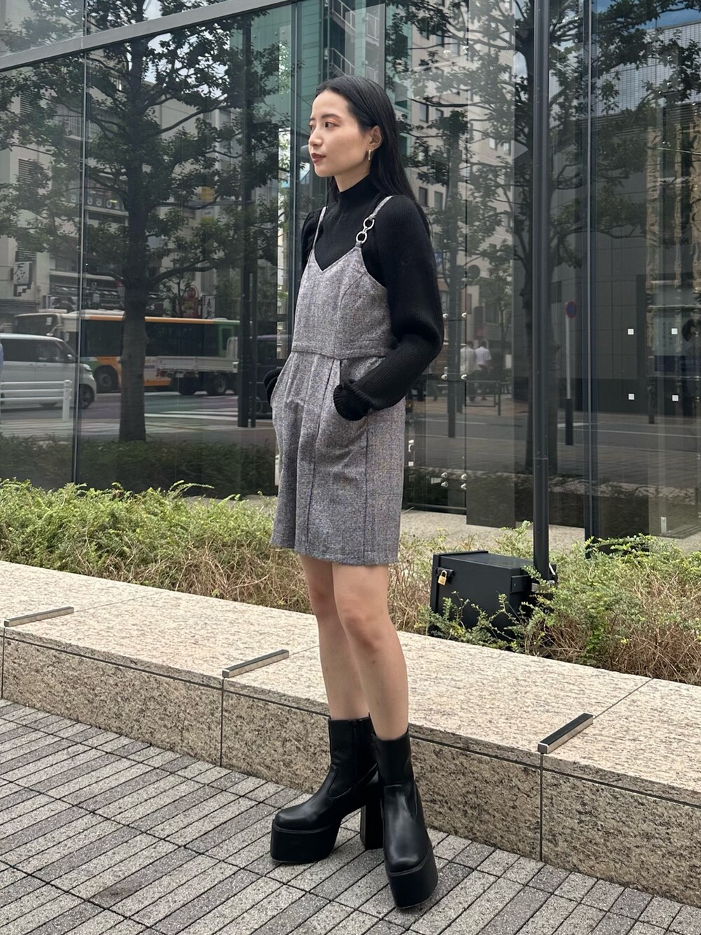 グレー系のワンピース、ブラック系のニット/セーター、ブラック系のブーツを着用したレディースの秋コーディネートの3枚目の写真