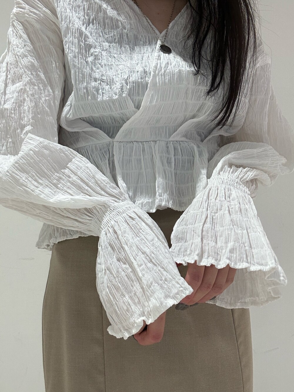 ホワイト系のシャツ/ブラウス、ベージュ系のスカート、ブラック系のブーツを着用したレディースの春コーディネートの5枚目の写真