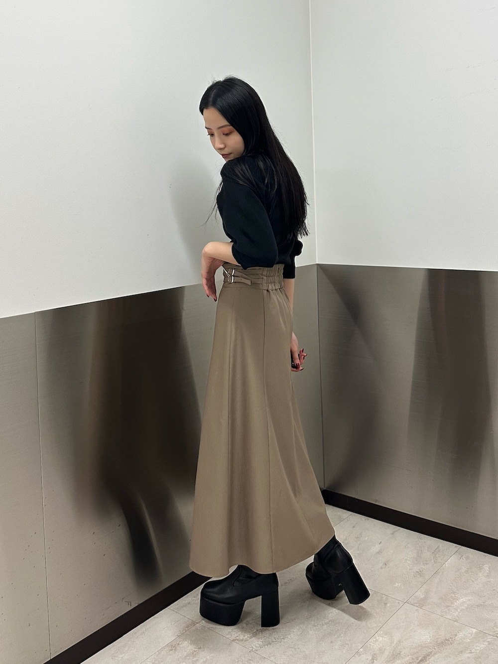 ベージュ系のスカート、ブラック系のニット/セーター、ブラック系のブーツを着用したレディースの夏コーディネートの4枚目の写真