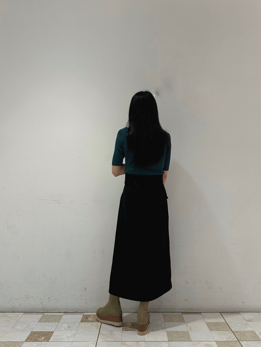 グリーン系のニット/セーター、ブラック系のスカート、ベージュ系のブーツを着用したレディースの春コーディネートの4枚目の写真