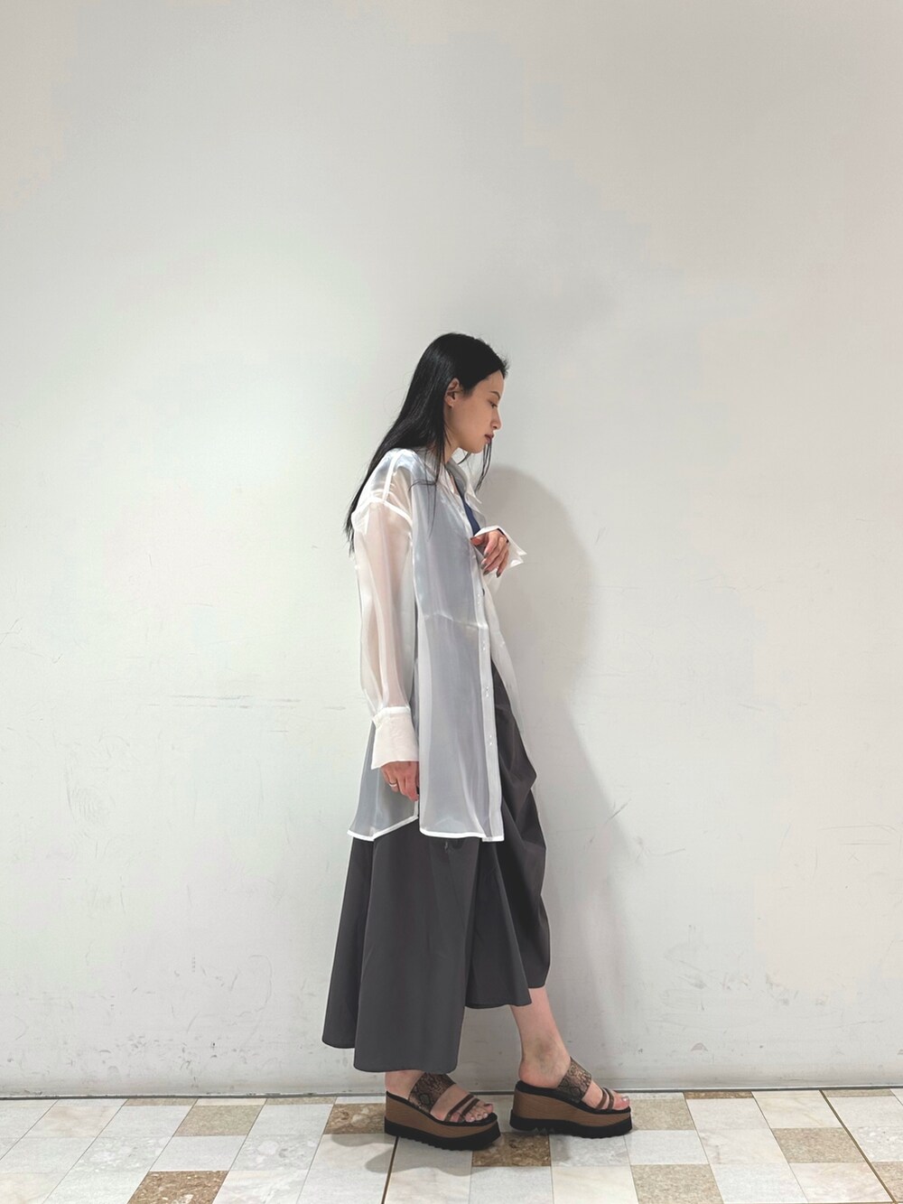 グレー系のスカート、ホワイト系のシャツ/ブラウス、ブルー系のタンクトップを着用したレディースの春コーディネートの2枚目の写真