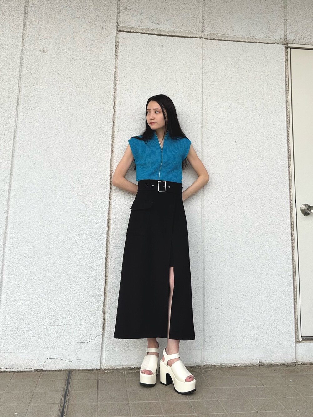 ブルー系のニット/セーター、ブラック系のスカート、ホワイト系のサンダルを着用したレディースの春コーディネートの2枚目の写真