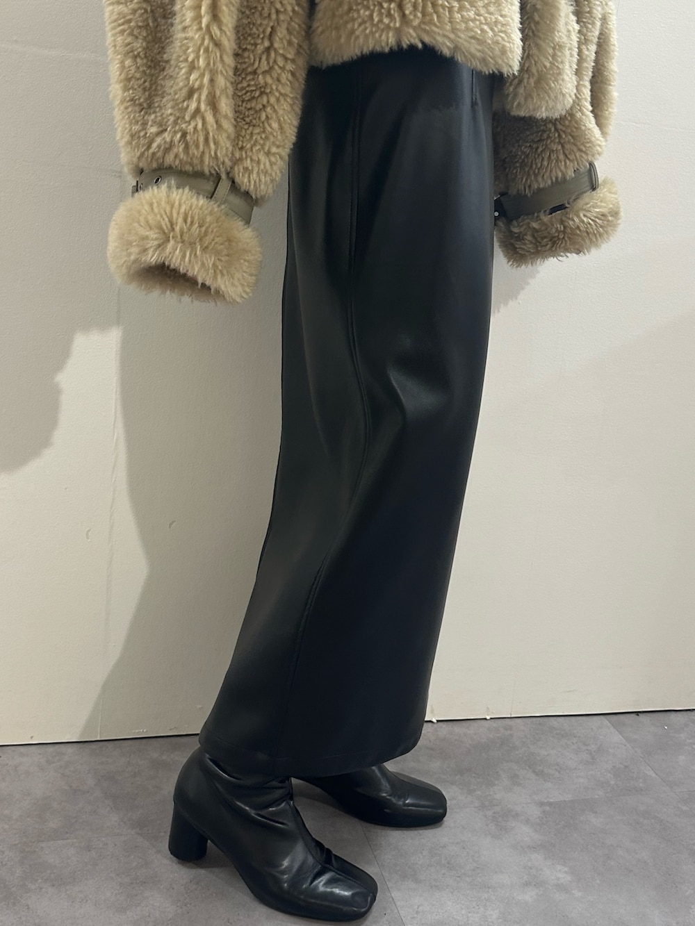 ブラック系のスカート、ブラウン系のムートンコート、レッド系のニット/セーターを着用したレディースの冬コーディネートの5枚目の写真