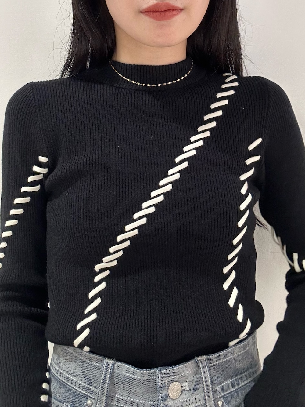 グレー系のデニムパンツ、ブラック系のブーツ、ブラック系のムートンコートを着用したレディースの夏コーディネートの5枚目の写真