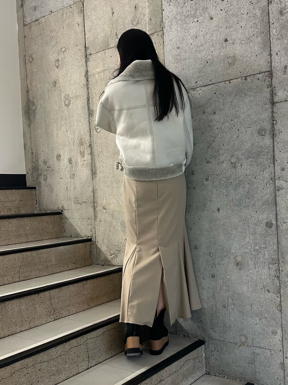 ベージュ系のスカート、グレー系のムートンコート、ブラック系のニット/セーターを着用したレディースの冬コーディネートの2枚目の写真