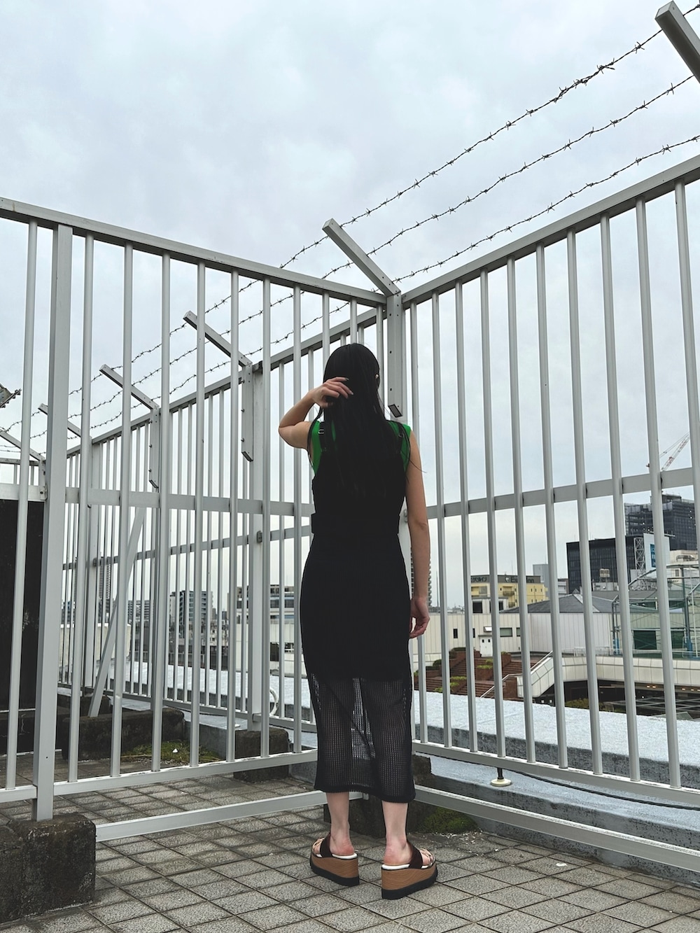 ブラック系のワンピース、グリーン系のタンクトップ、その他のサンダルを着用したレディースの春コーディネートの4枚目の写真