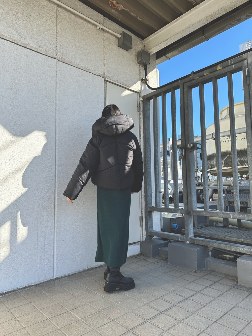 ブラック系のダウンジャケット/コート、グリーン系のワンピース、ブラック系のブーツを着用したレディースの秋コーディネートの2枚目の写真