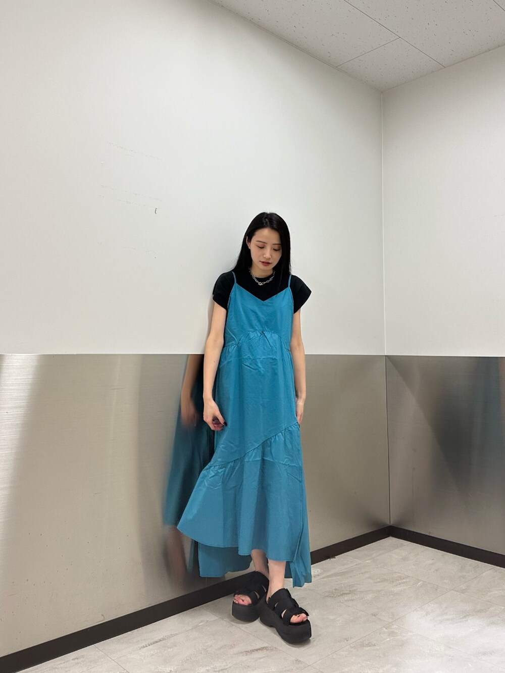 ブルー系のワンピース、ブラック系のTシャツ/カットソー、ブラック系のサンダルを着用したレディースの春コーディネートの2枚目の写真