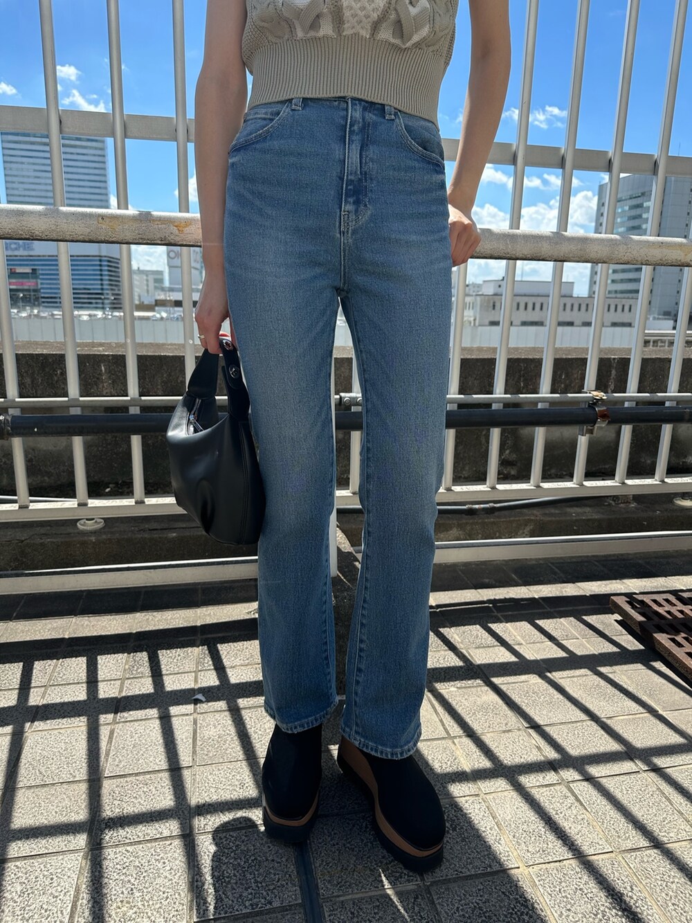 ホワイト系のニット/セーター、ブルー系のデニムパンツ、ブラック系のブーツを着用したレディースの夏コーディネートの6枚目の写真