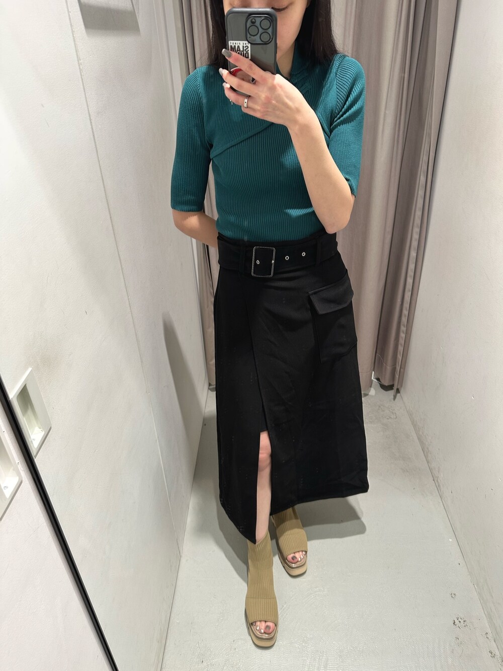 グリーン系のニット/セーター、ブラック系のスカート、ベージュ系のブーツを着用したレディースの春コーディネートの6枚目の写真