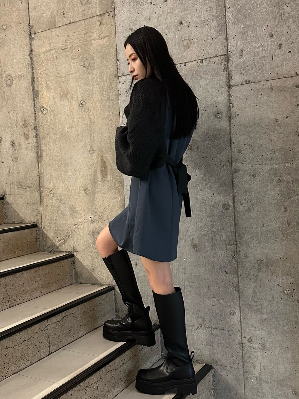 グレー系のワンピース、グレー系のダウンジャケット/コート、ブラック系のブーツを着用したレディースの冬コーディネートの6枚目の写真