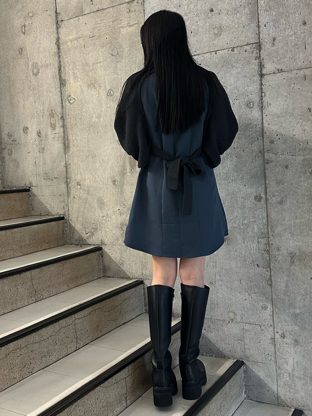 グレー系のワンピース、グレー系のダウンジャケット/コート、ブラック系のブーツを着用したレディースの冬コーディネートの5枚目の写真