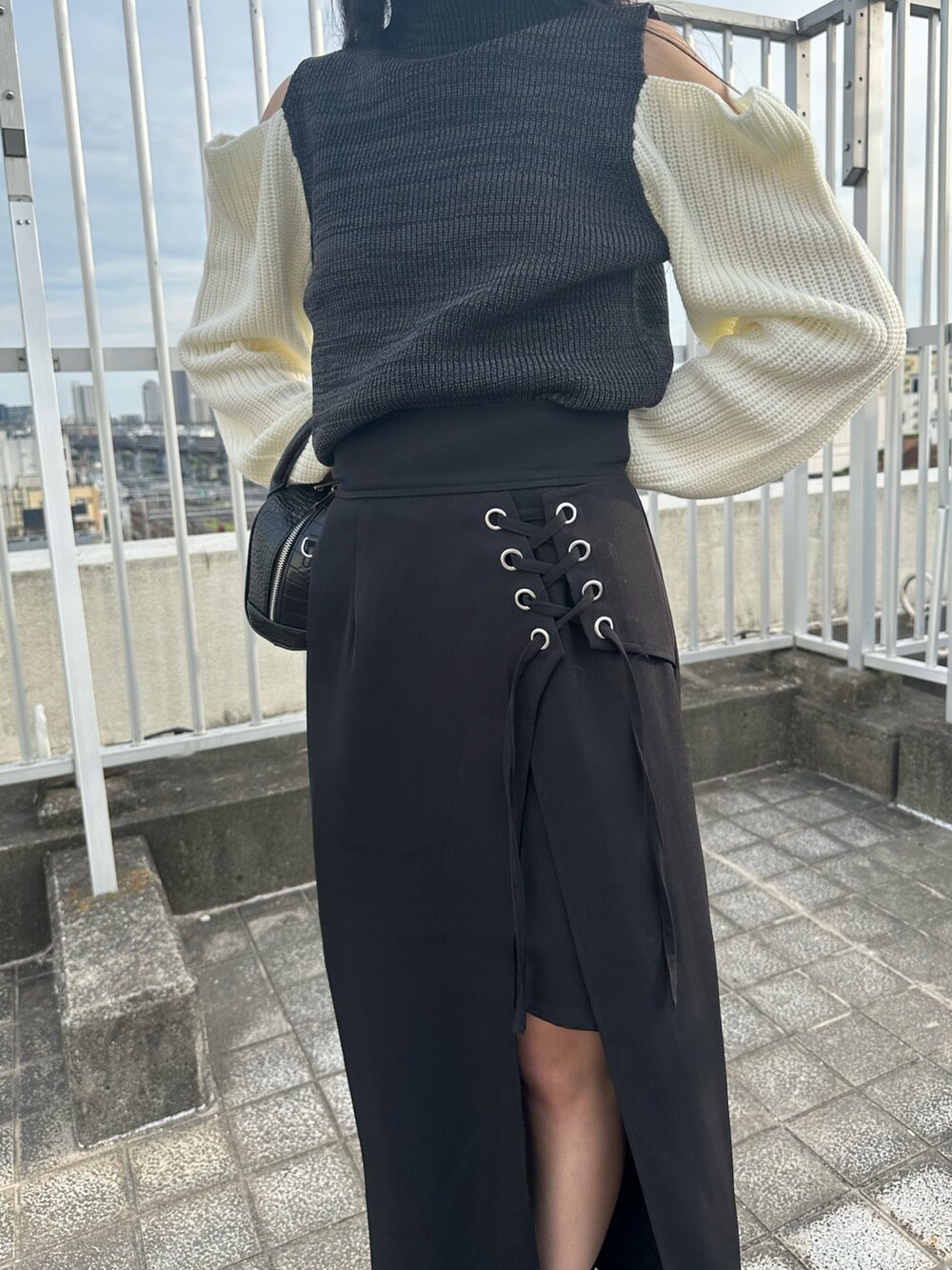 ブラック系のニット/セーター、ブラック系のスカート、ブラック系のブーツを着用したレディースの夏コーディネートの7枚目の写真