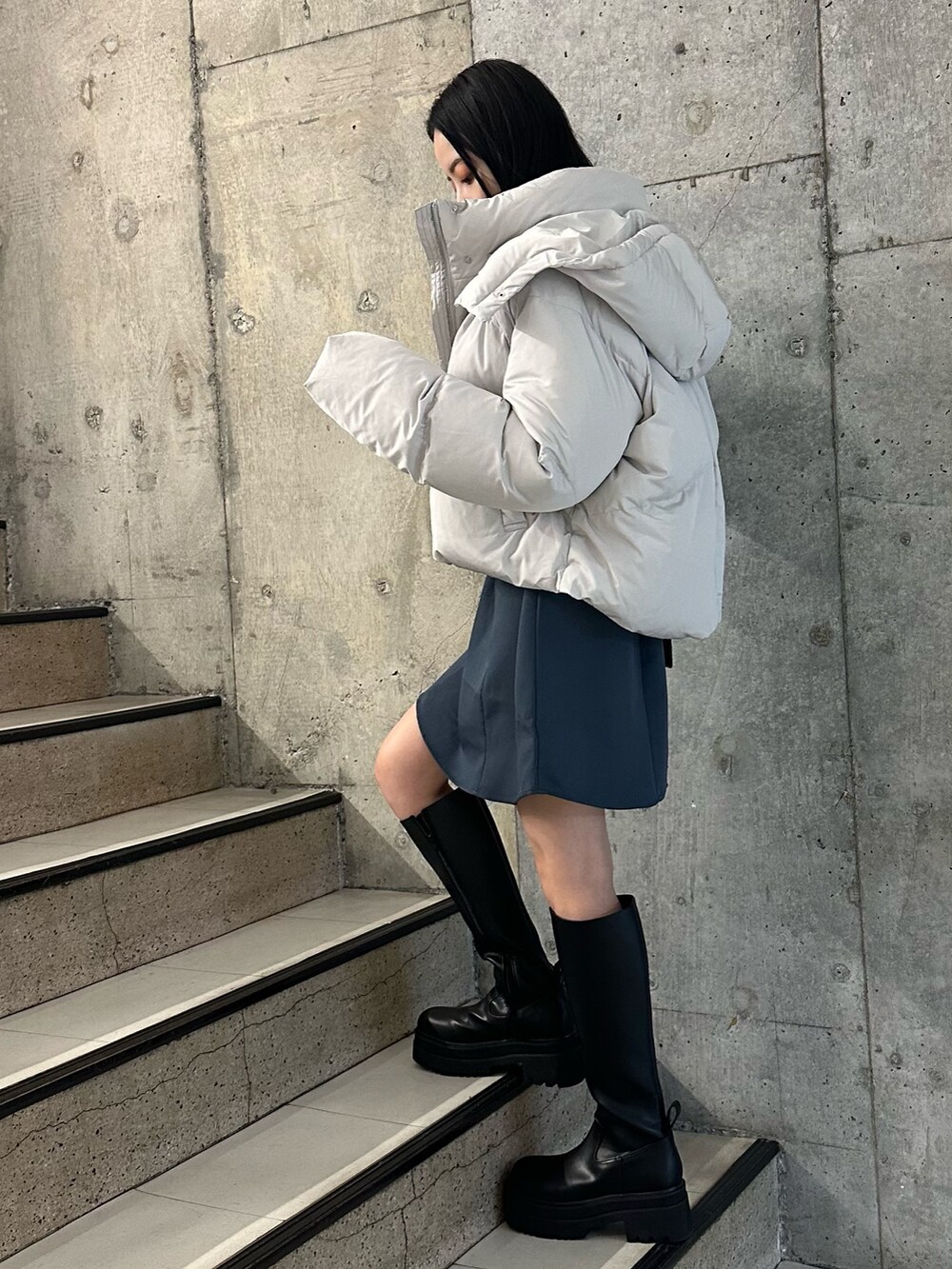 グレー系のワンピース、グレー系のダウンジャケット/コート、ブラック系のブーツを着用したレディースの冬コーディネートの3枚目の写真