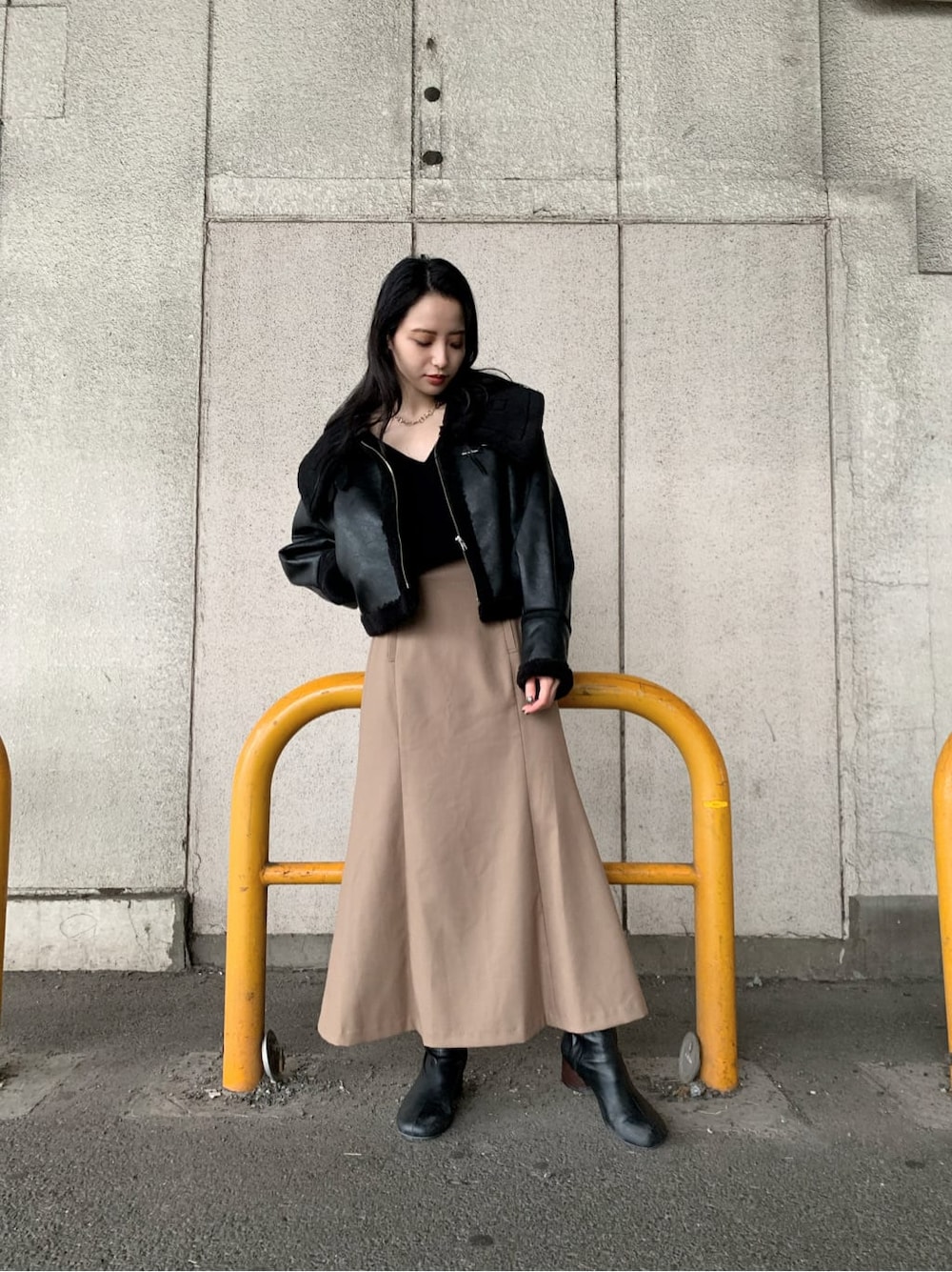 ブラウン系のスカート、ブラック系のブーツ、ブラック系のニット/セーターを着用したレディースの秋コーディネートの2枚目の写真