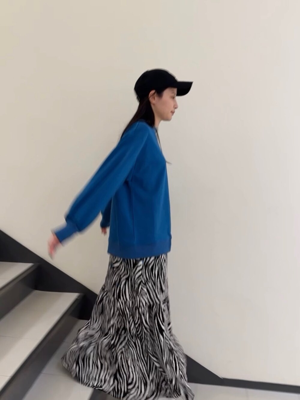 ブルー系のTシャツ/カットソー、ホワイト系のスカート、ブラック系のキャップを着用したレディースの春コーディネートの3枚目の写真