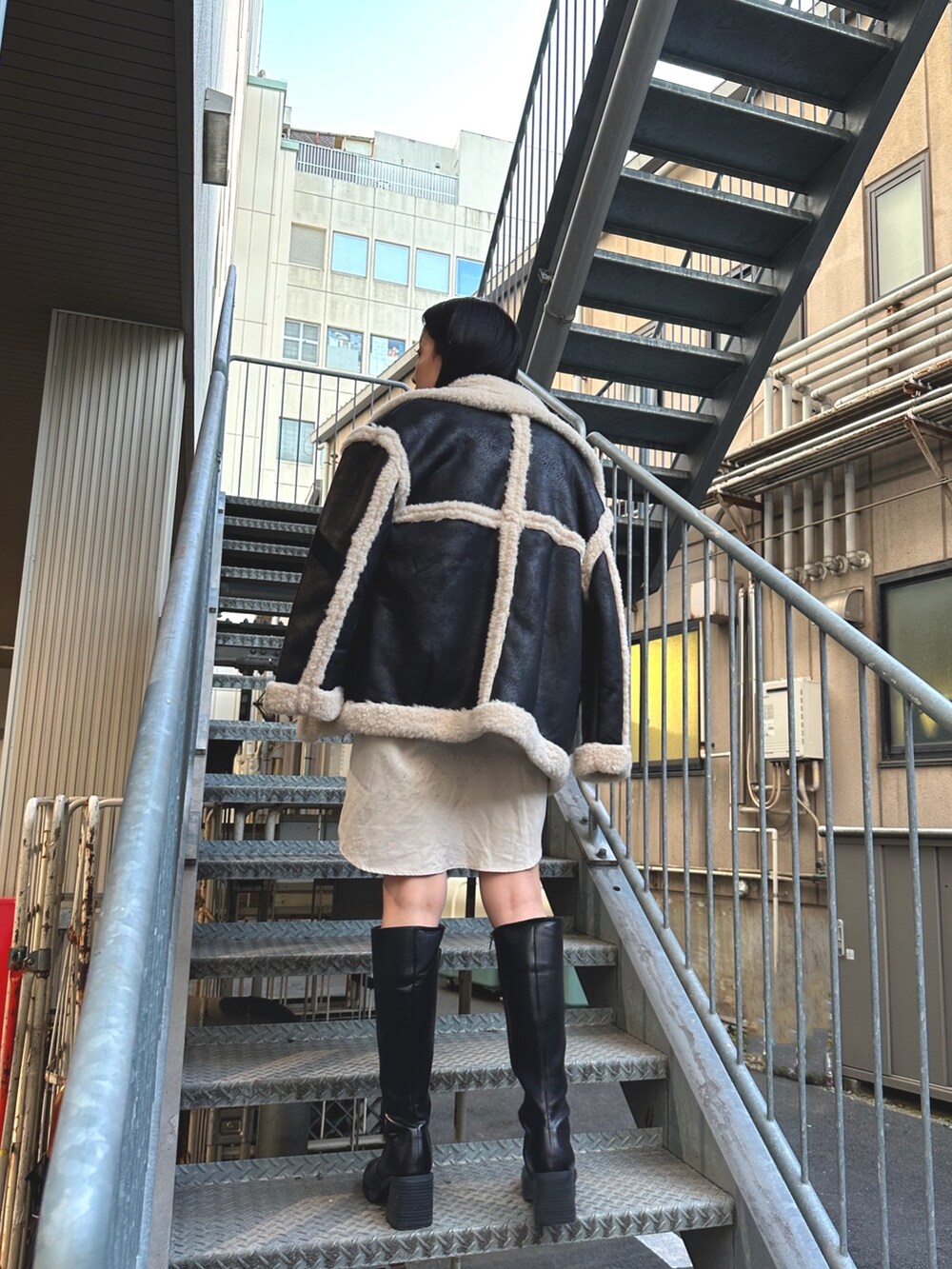 ホワイト系のワンピース、ブラック系のムートンコートを着用したレディースの冬コーディネートの2枚目の写真