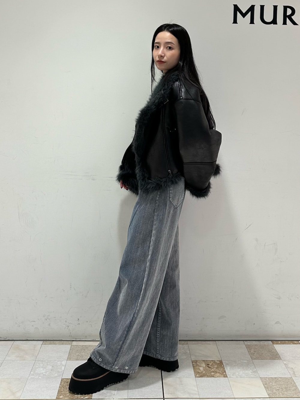 グレー系のデニムパンツ、ブラック系のブーツ、ブラック系のムートンコートを着用したレディースの夏コーディネートの3枚目の写真