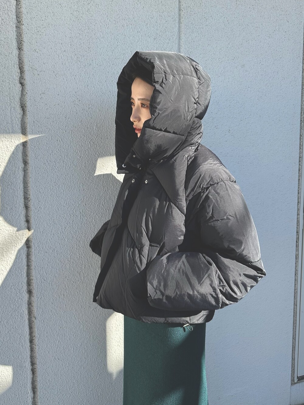 ブラック系のダウンジャケット/コート、グリーン系のワンピース、ブラック系のブーツを着用したレディースの秋コーディネートの4枚目の写真