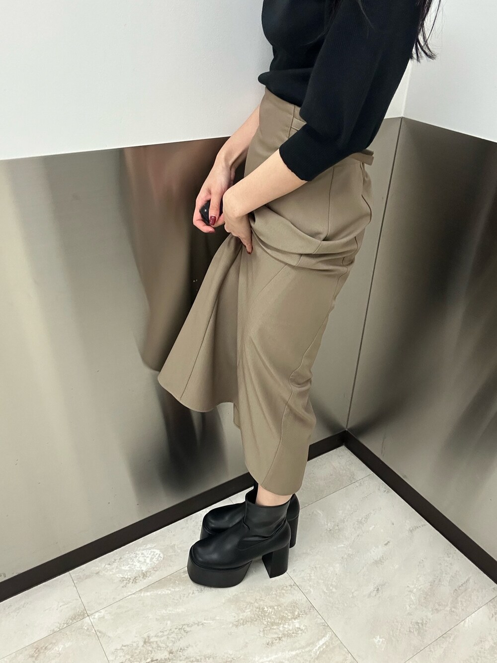 ベージュ系のスカート、ブラック系のニット/セーター、ブラック系のブーツを着用したレディースの夏コーディネートの9枚目の写真