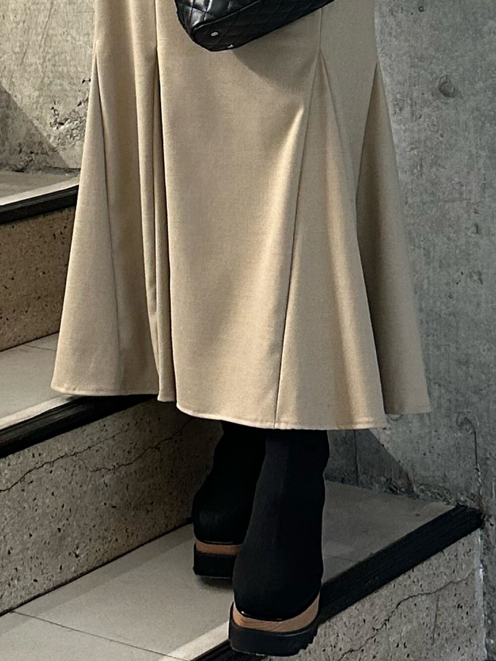 ベージュ系のスカート、グレー系のムートンコート、ブラック系のニット/セーターを着用したレディースの冬コーディネートの7枚目の写真