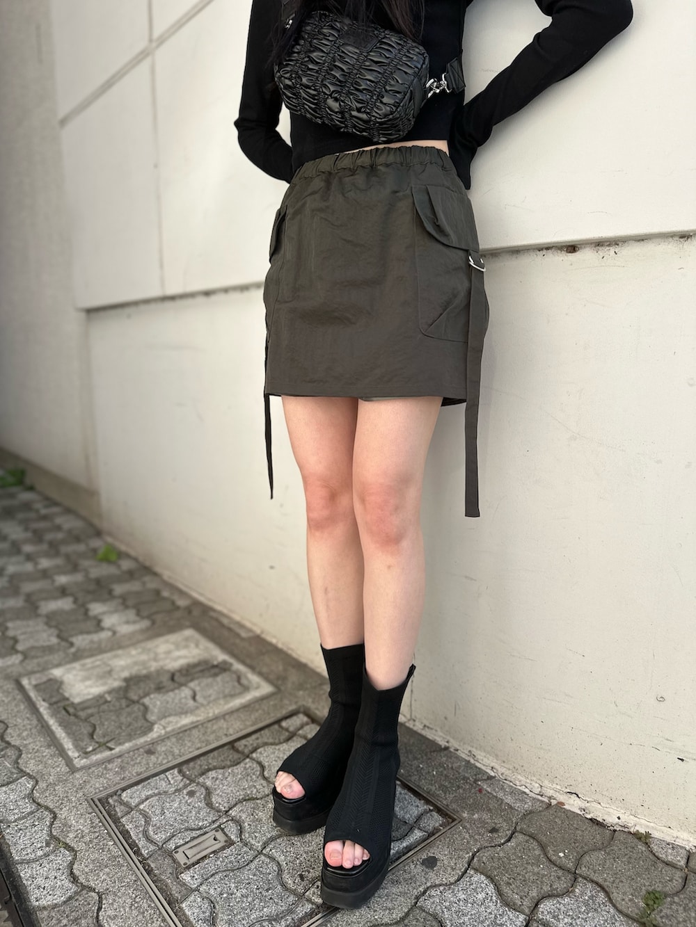 ベージュ系のスカート、ブラック系のTシャツ/カットソー、ブラック系のブーツを着用したレディースの冬コーディネートの3枚目の写真