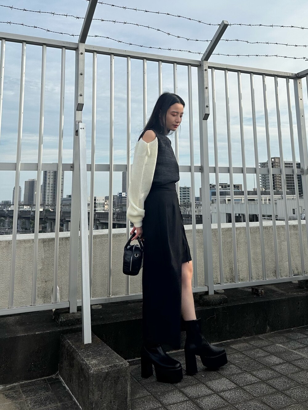 ブラック系のニット/セーター、ブラック系のスカート、ブラック系のブーツを着用したレディースの夏コーディネートの3枚目の写真