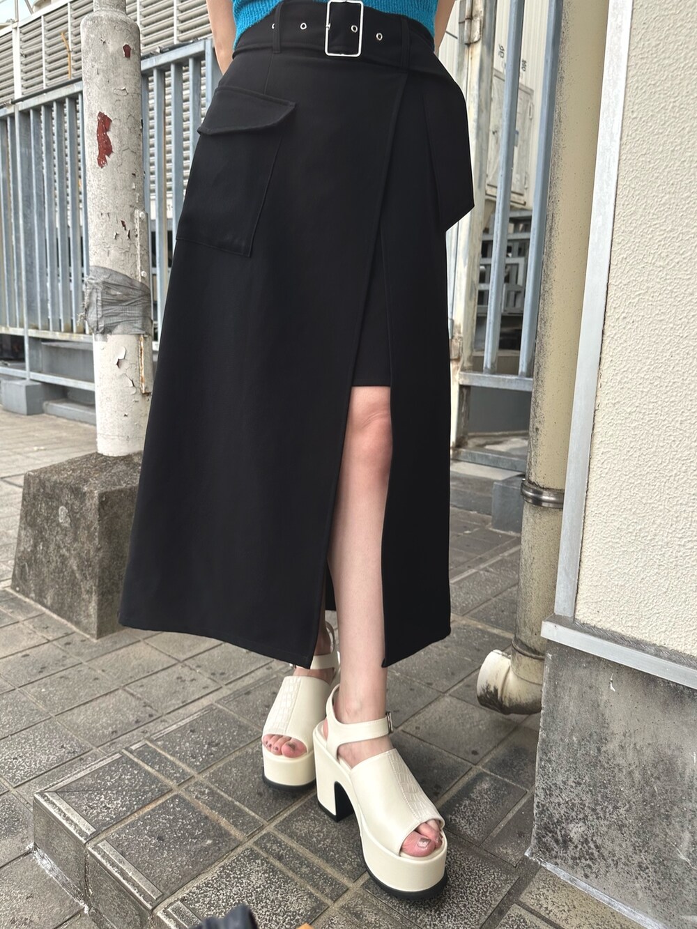 ブルー系のニット/セーター、ブラック系のスカート、ホワイト系のサンダルを着用したレディースの春コーディネートの7枚目の写真