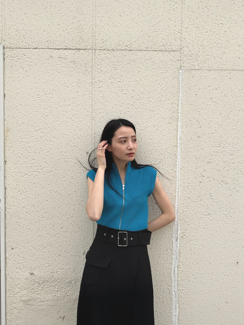 ブルー系のニット/セーター、ブラック系のスカート、ホワイト系のサンダルを着用したレディースの春コーディネートの5枚目の写真