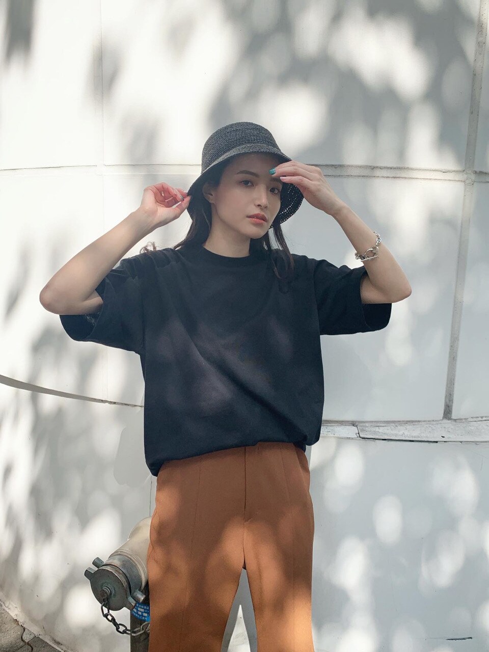 ブラック系のTシャツ/カットソー、ブラウン系のスラックス、ブラック系のハットを着用したレディースの春コーディネートの3枚目の写真