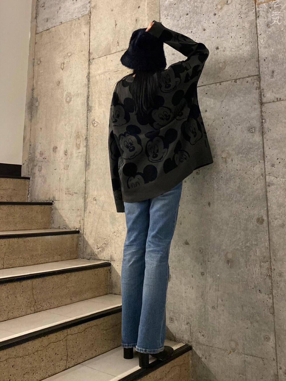 ブルー系のデニムパンツ、ブラック系のブーツ、グレー系のニット/セーターを着用したレディースの秋コーディネートの4枚目の写真