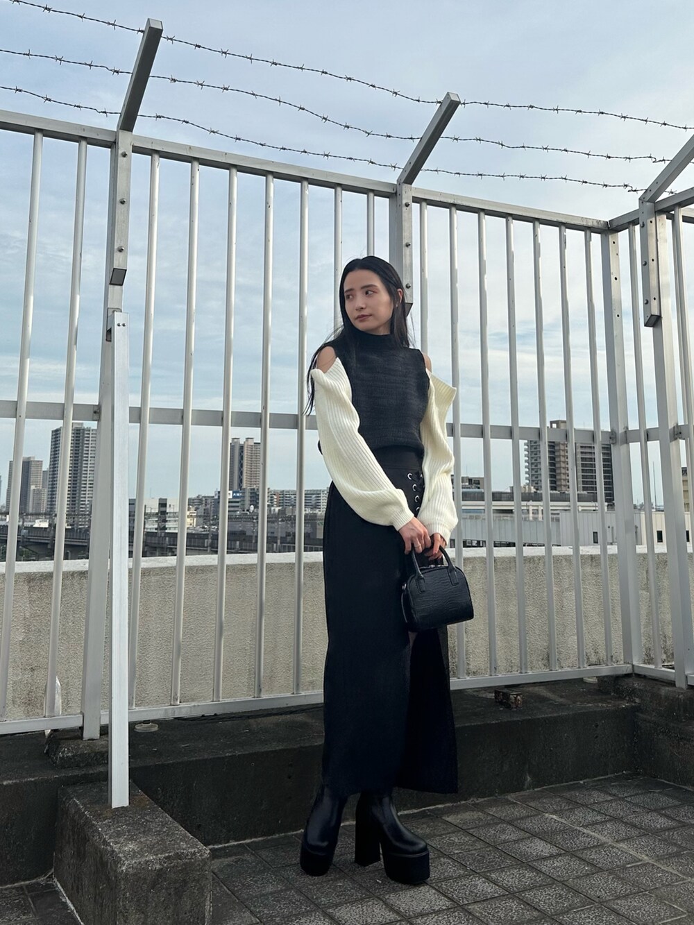 ブラック系のニット/セーター、ブラック系のスカート、ブラック系のブーツを着用したレディースの夏コーディネートの6枚目の写真