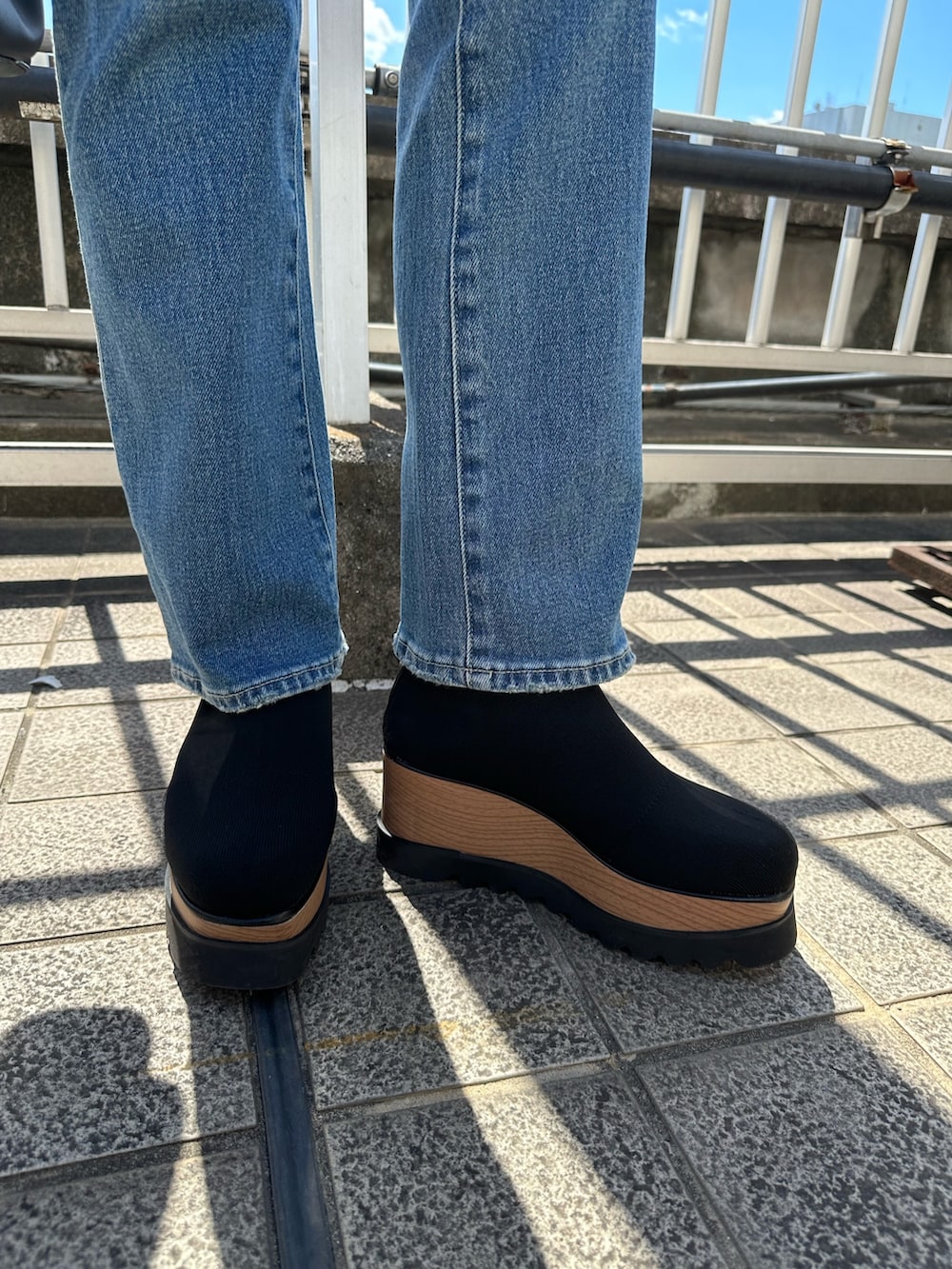 ホワイト系のニット/セーター、ブルー系のデニムパンツ、ブラック系のブーツを着用したレディースの夏コーディネートの8枚目の写真