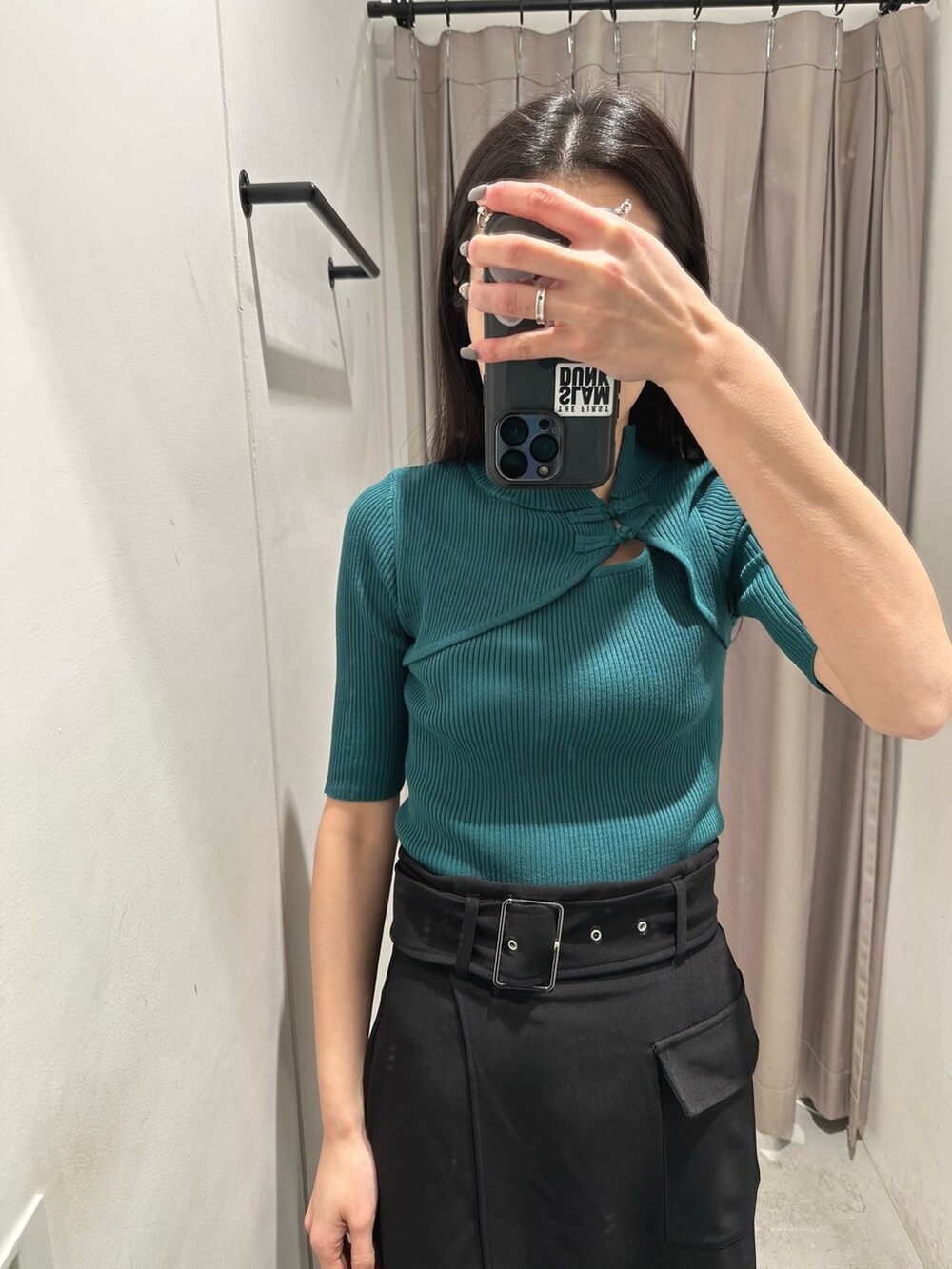 グリーン系のニット/セーター、ブラック系のスカート、ベージュ系のブーツを着用したレディースの春コーディネートの7枚目の写真