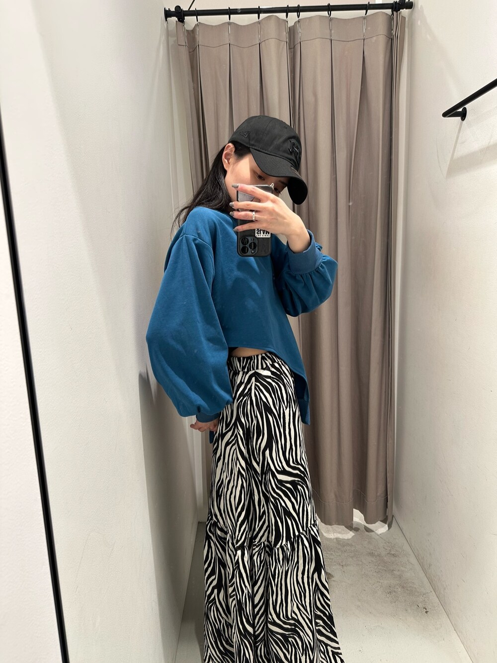 ブルー系のTシャツ/カットソー、ホワイト系のスカート、ブラック系のキャップを着用したレディースの春コーディネートの5枚目の写真