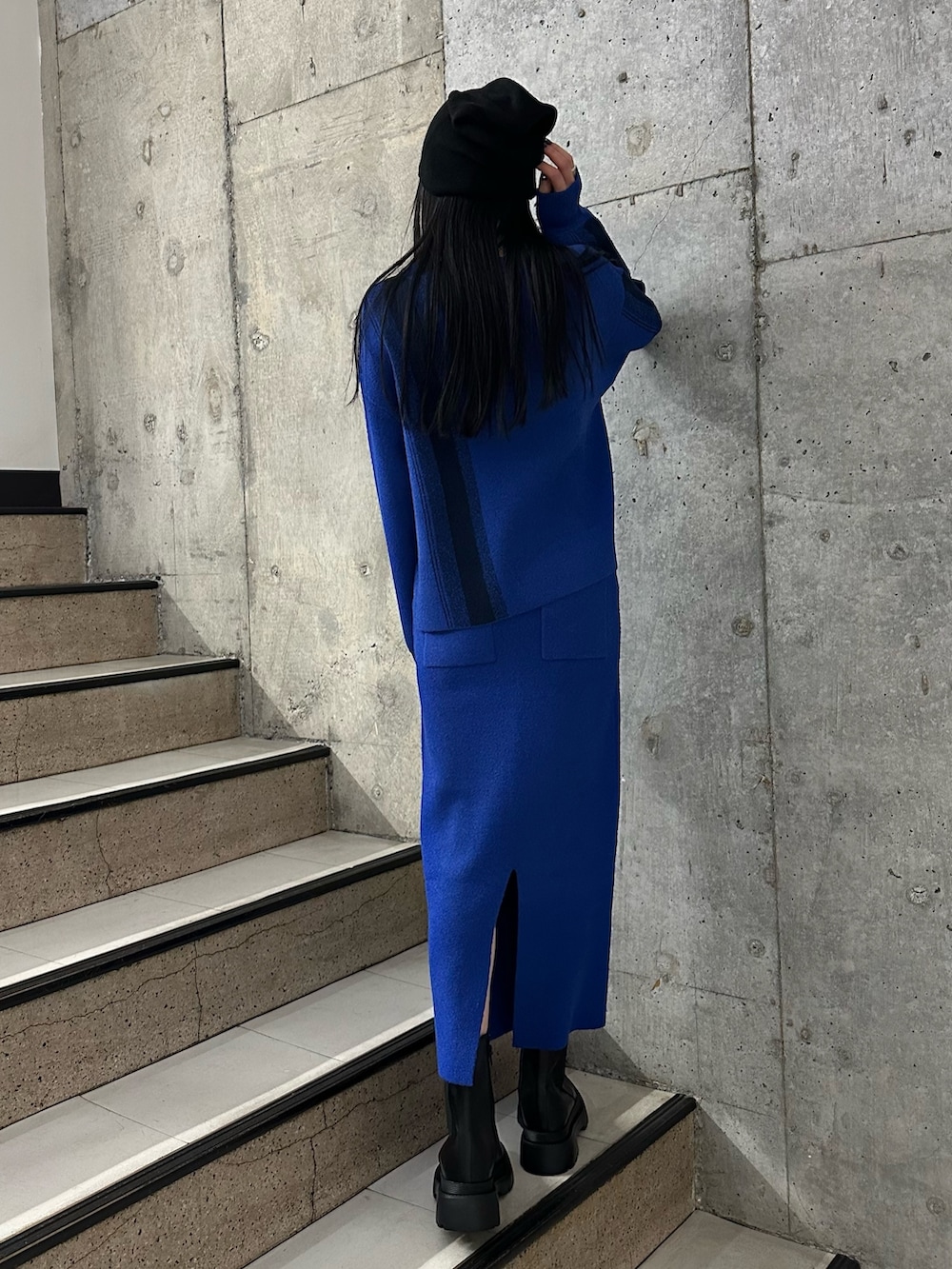 ブルー系のニット/セーター、ブルー系のスカート、ブラック系のブーツを着用したレディースの冬コーディネートの3枚目の写真