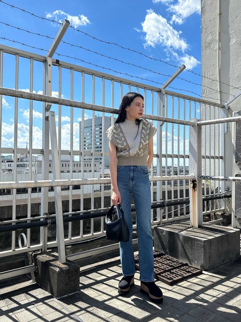 ホワイト系のニット/セーター、ブルー系のデニムパンツ、ブラック系のブーツを着用したレディースの夏コーディネートの2枚目の写真