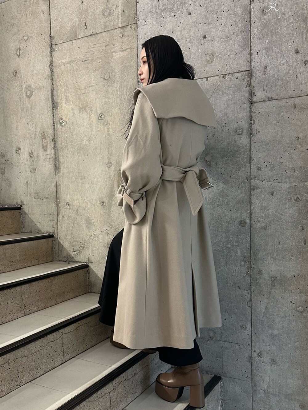 ブラック系のスカート、ホワイト系のニット/セーター、ブラウン系のブーツを着用したレディースの冬コーディネートの2枚目の写真