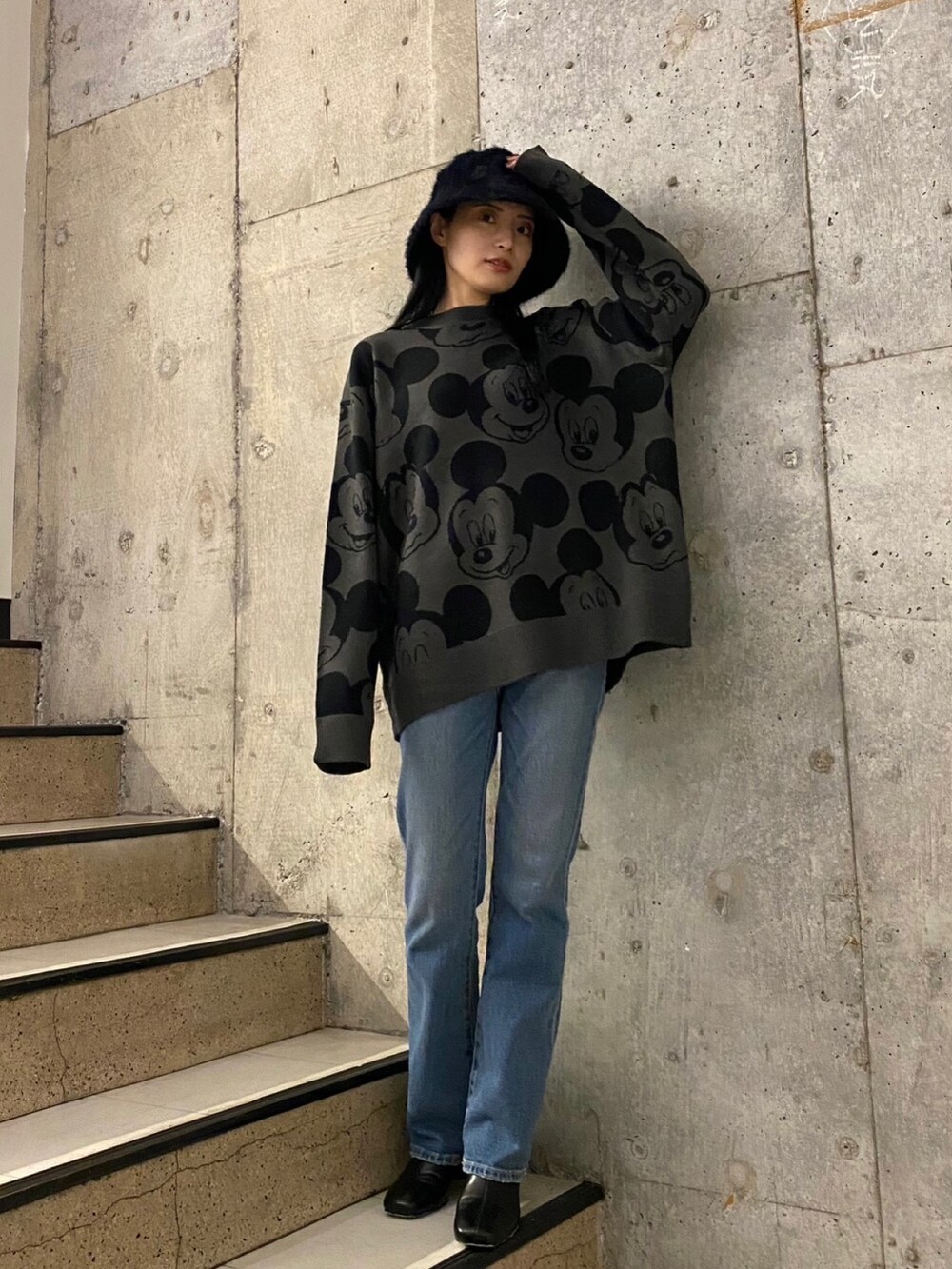 ブルー系のデニムパンツ、ブラック系のブーツ、グレー系のニット/セーターを着用したレディースの秋コーディネートの2枚目の写真