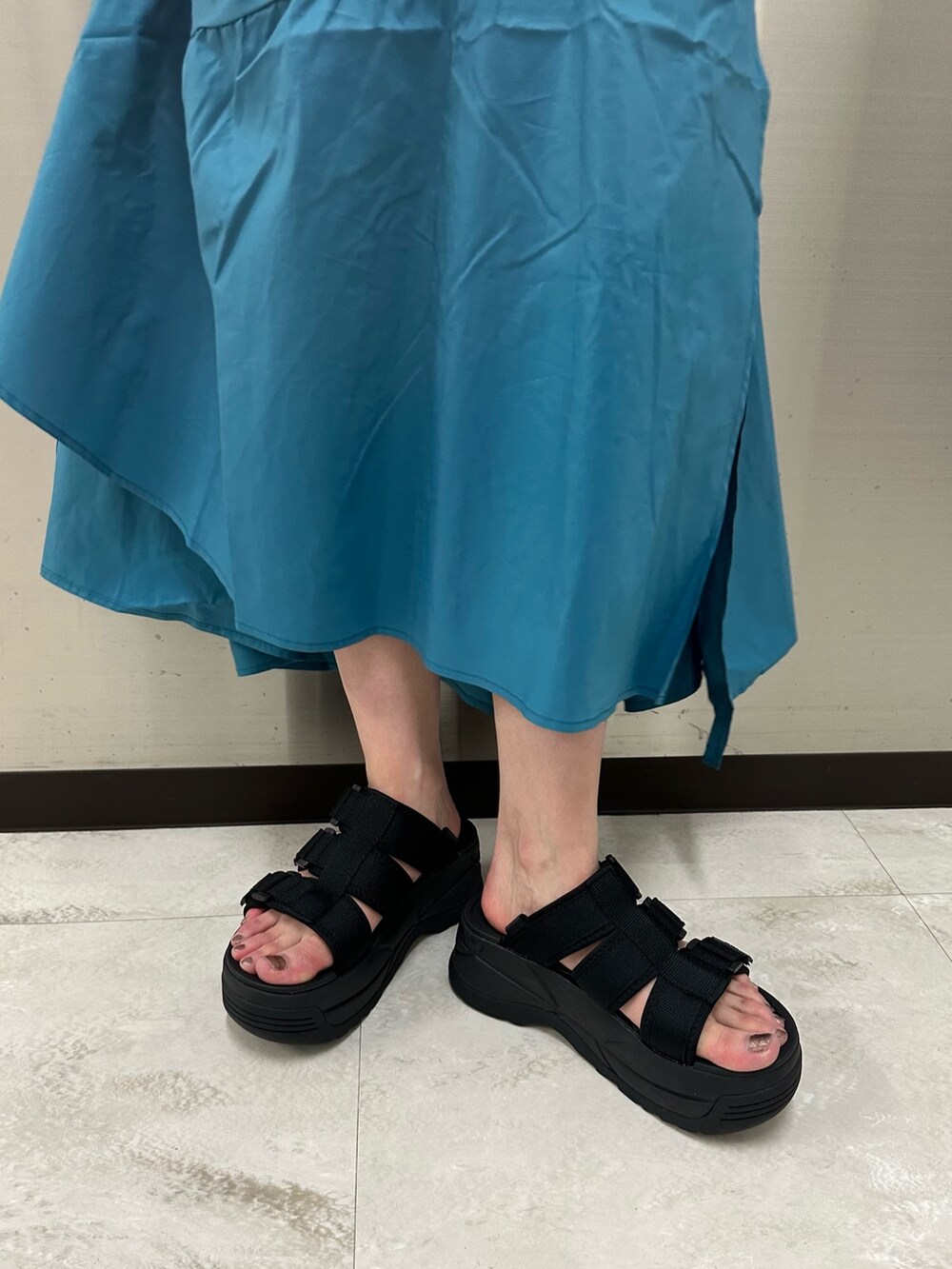 ブルー系のワンピース、ブラック系のTシャツ/カットソー、ブラック系のサンダルを着用したレディースの春コーディネートの6枚目の写真