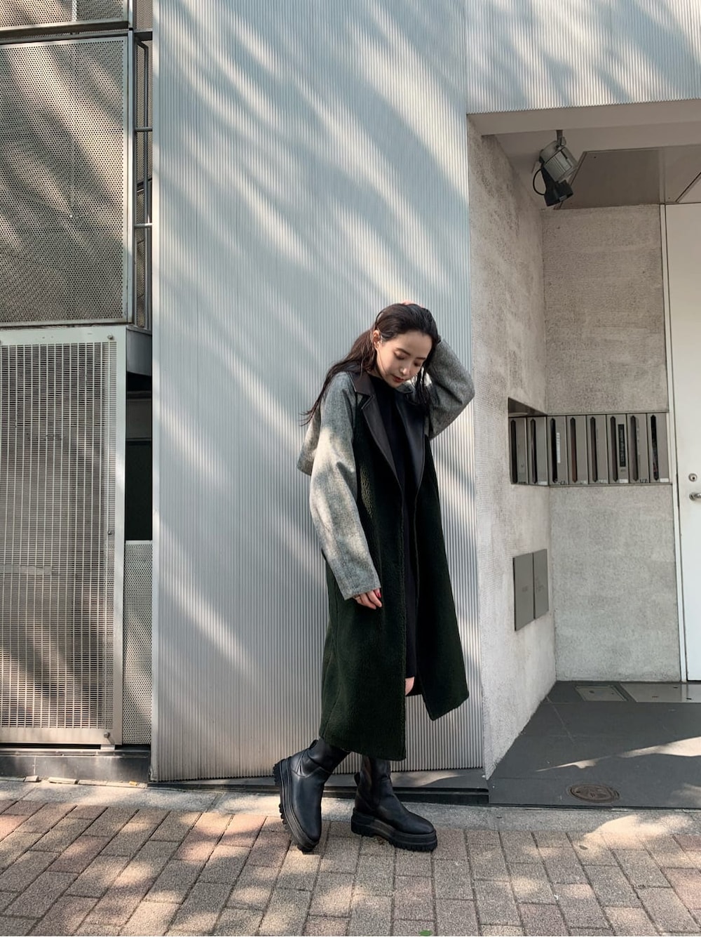 ブラック系のチェスターコート、ブラック系のワンピース、ブラック系のブーツを着用したレディースの秋コーディネートの3枚目の写真