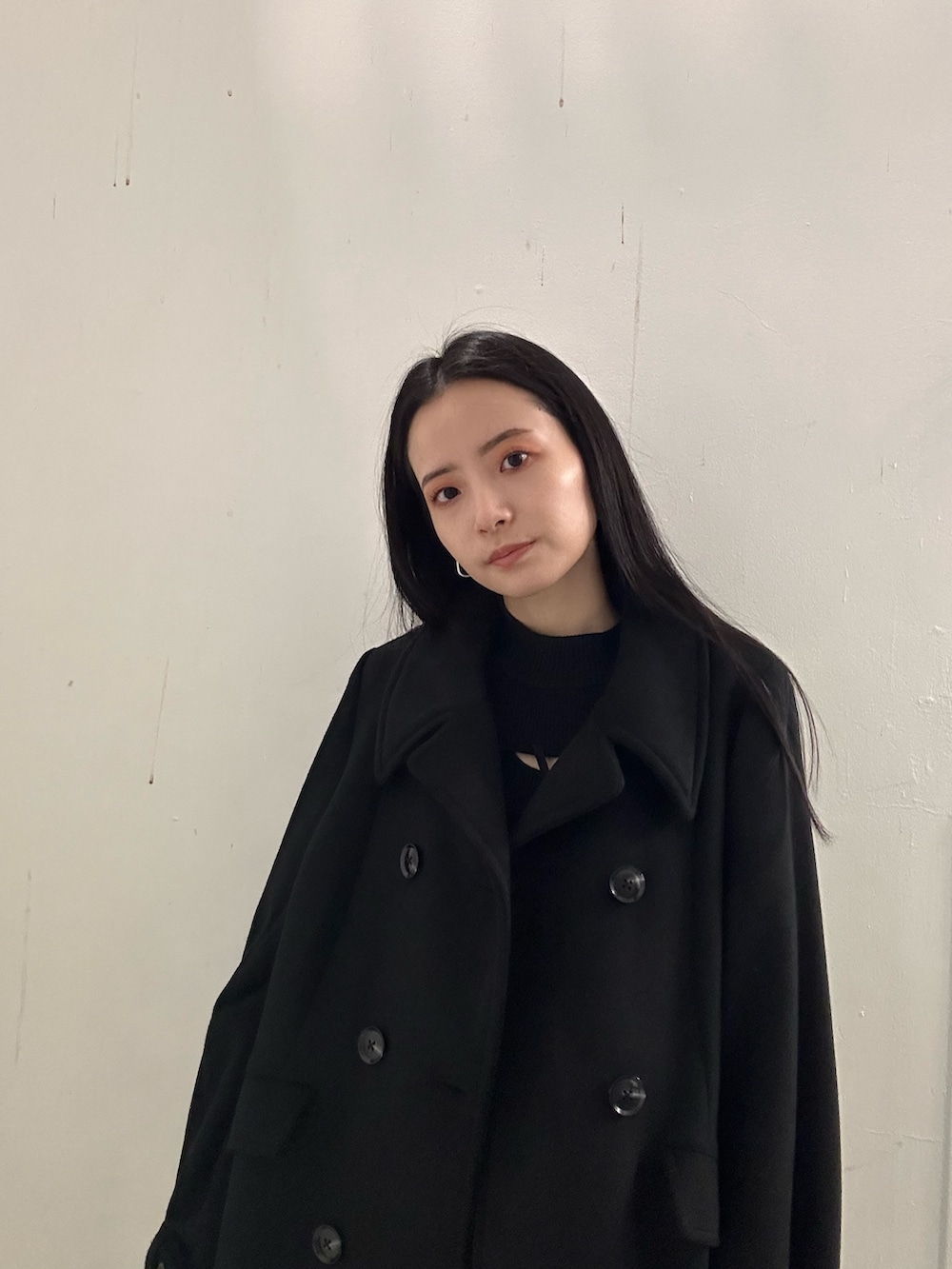 ブラック系のブーツ、ブラック系のチェスターコート、ブラック系のニット/セーターを着用したレディースの冬コーディネートの4枚目の写真