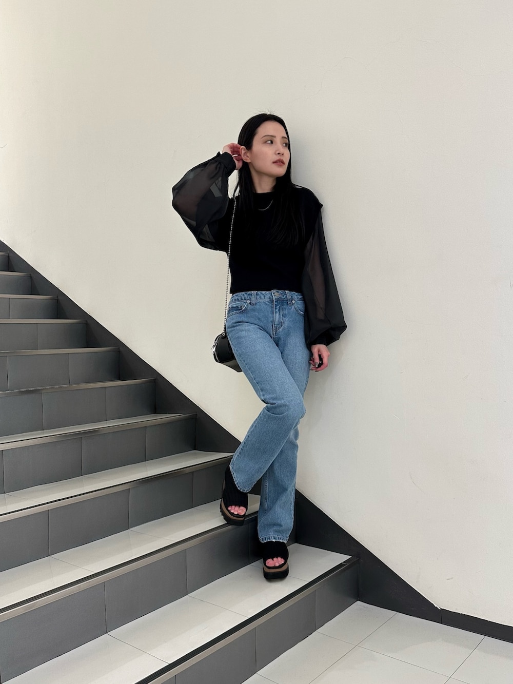 ブラック系のニット/セーター、ブルー系のデニムパンツを着用したレディースの春コーディネートの3枚目の写真