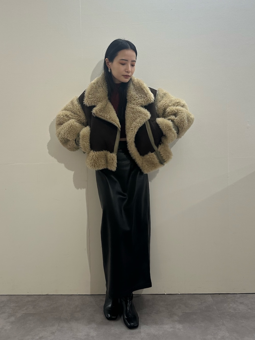 ブラック系のスカート、ブラウン系のムートンコート、レッド系のニット/セーターを着用したレディースの冬コーディネートの8枚目の写真