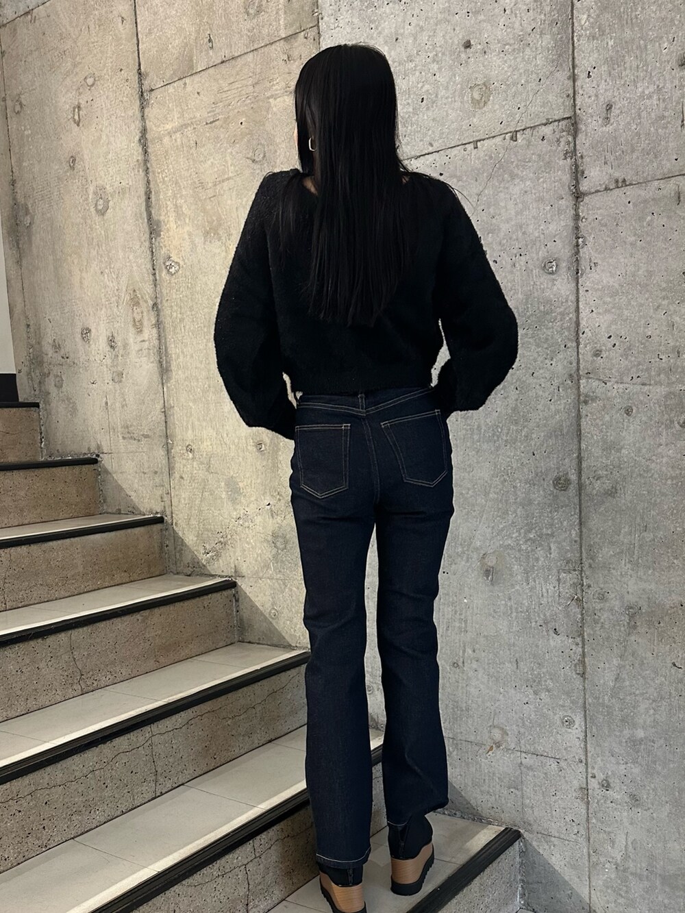 ブラック系のチェスターコート、ブラック系のブーツ、ブラック系のニット/セーターを着用したレディースの秋コーディネートの5枚目の写真