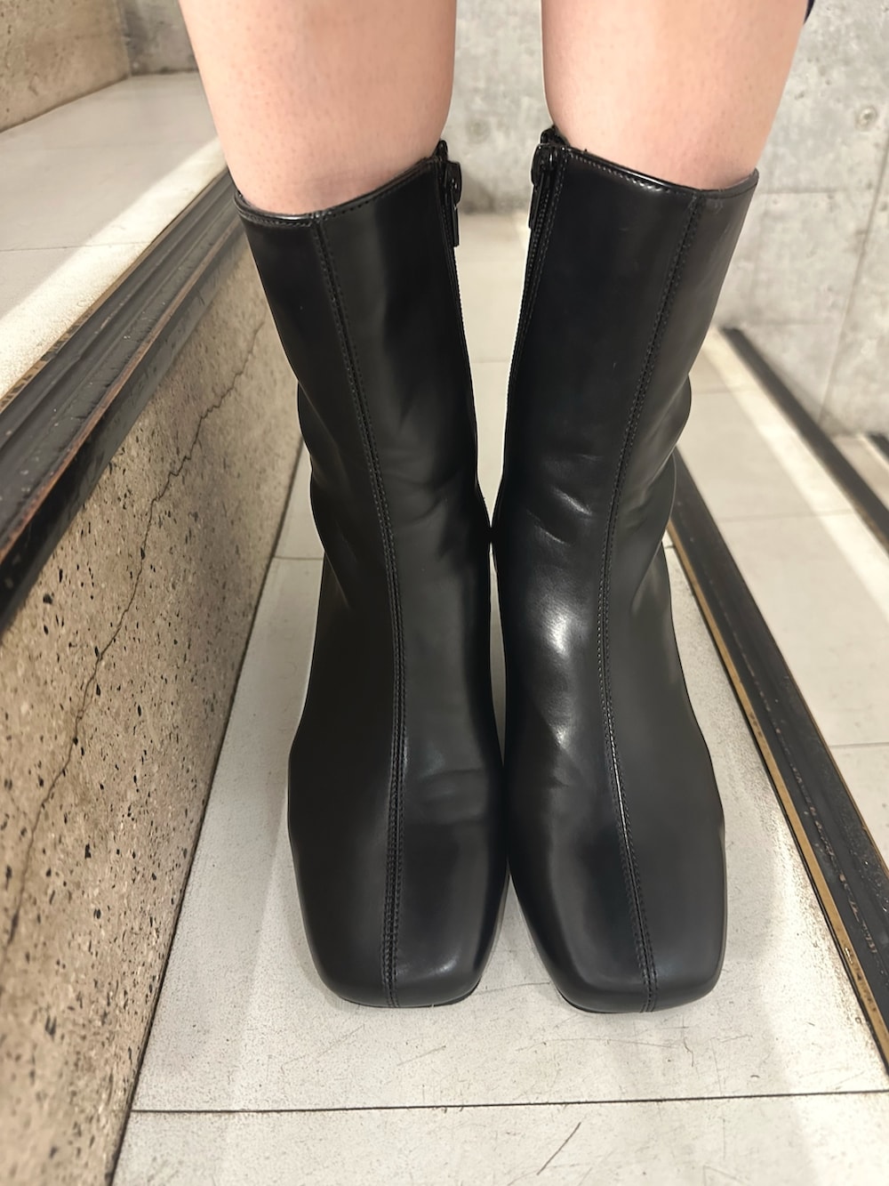 グレー系のスラックス、ブラック系のブーツ、グレー系のテーラードジャケットを着用したレディースの秋コーディネートの7枚目の写真