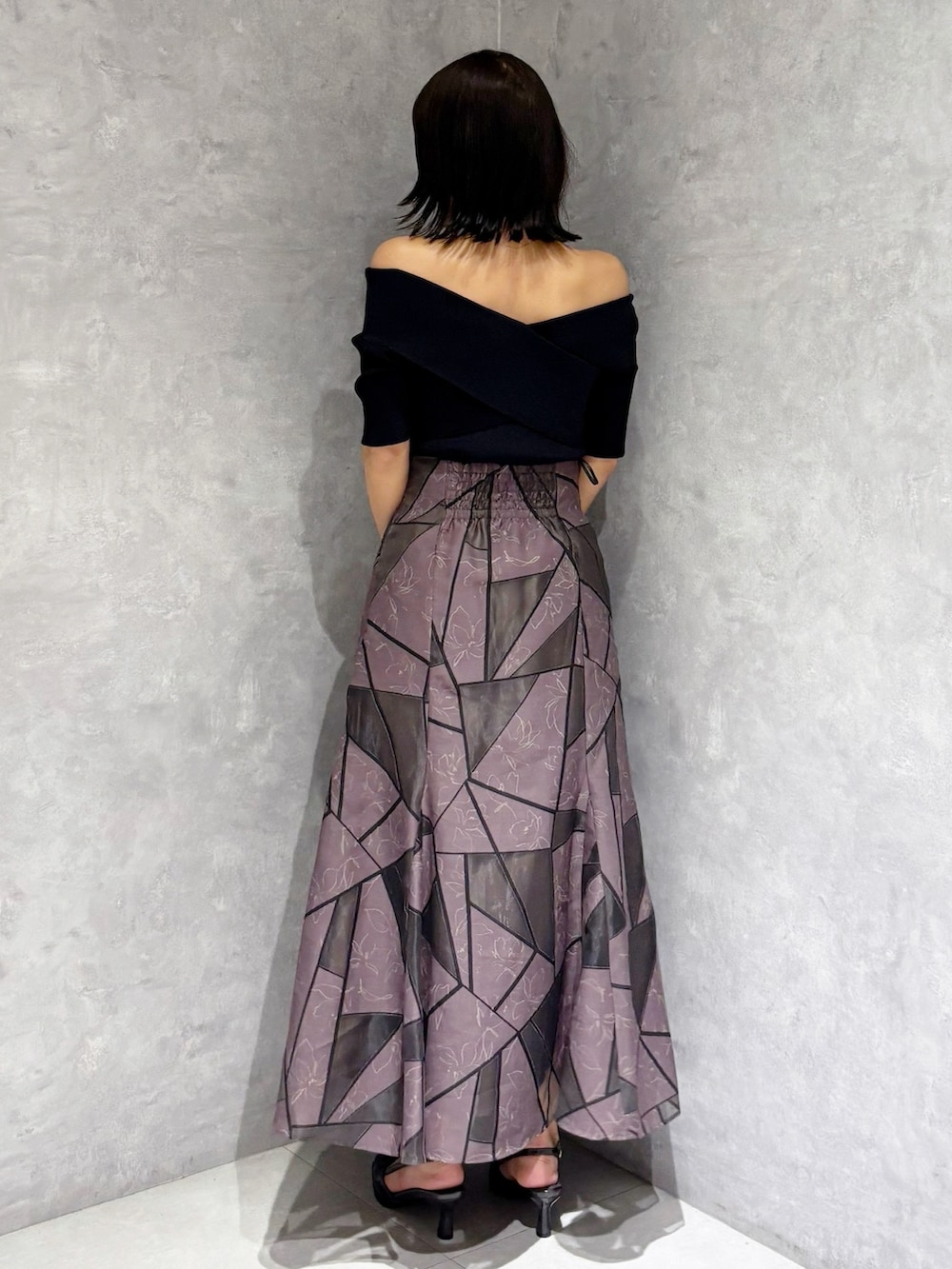 ブラウン系のスカート、ブラック系のハンドバッグ、ブラック系のニット/セーターを着用したレディースの夏コーディネートの2枚目の写真