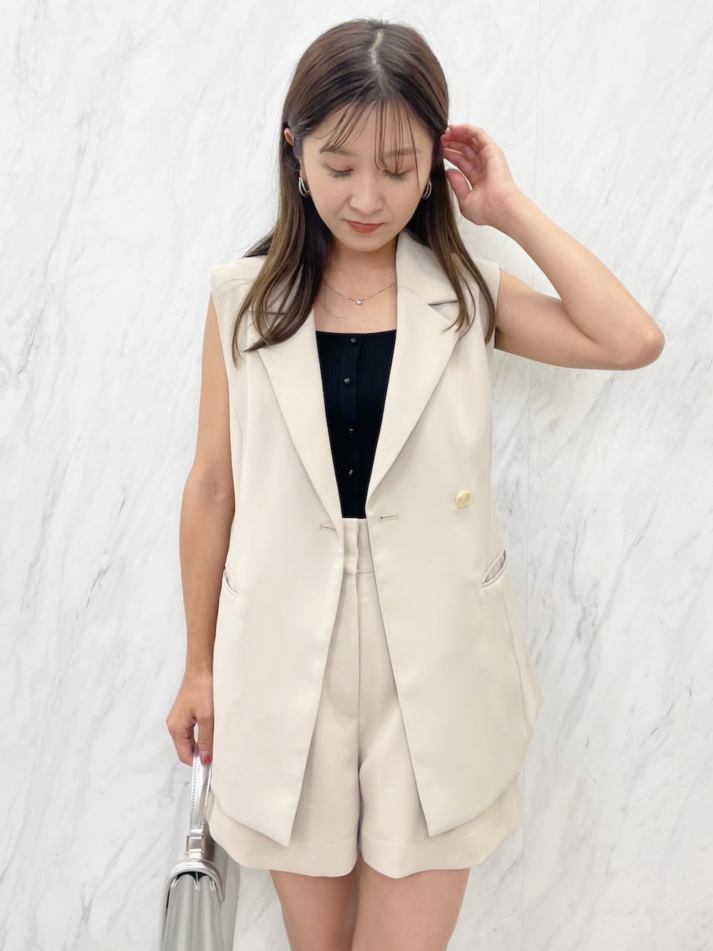 ブラウン系のサンダル、シルバー系のハンドバッグ、ベージュ系のベストを着用したレディースの夏コーディネートの3枚目の写真