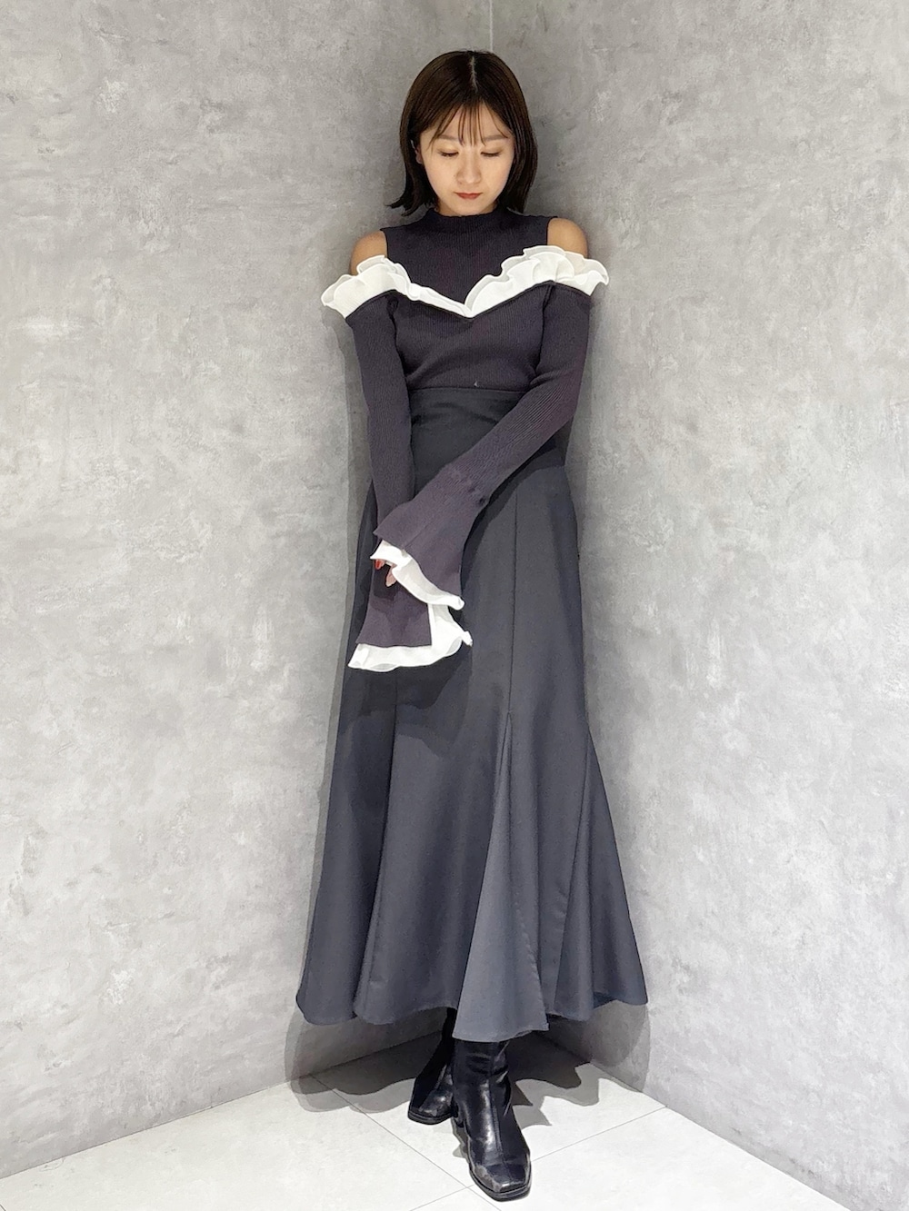 グレー系のスカート、グレー系のニット/セーター、ブラック系のブーツを着用したレディースの冬コーディネートの6枚目の写真